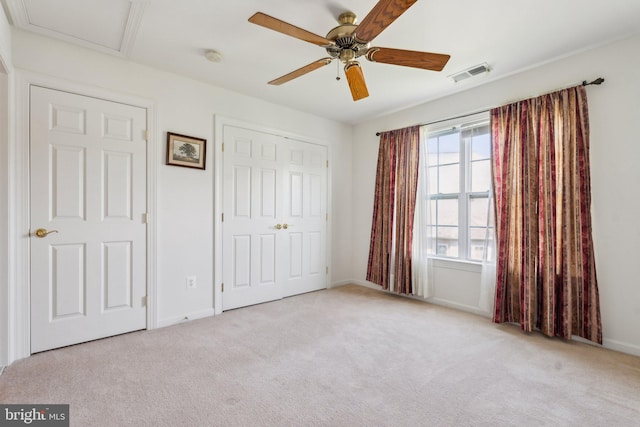 unfurnished bedroom with baseboards, visible vents, carpet floors, and ceiling fan