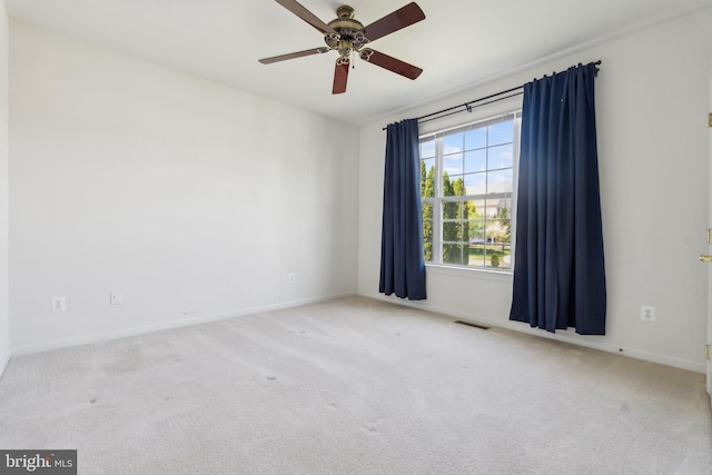 carpeted spare room with baseboards, a ceiling fan, and visible vents