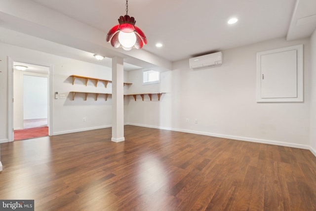 finished below grade area with recessed lighting, a wall mounted air conditioner, baseboards, and wood finished floors