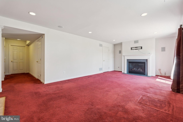 unfurnished living room featuring a fireplace with flush hearth, carpet flooring, and recessed lighting