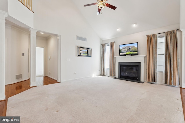 unfurnished living room featuring decorative columns, visible vents, high vaulted ceiling, and a ceiling fan