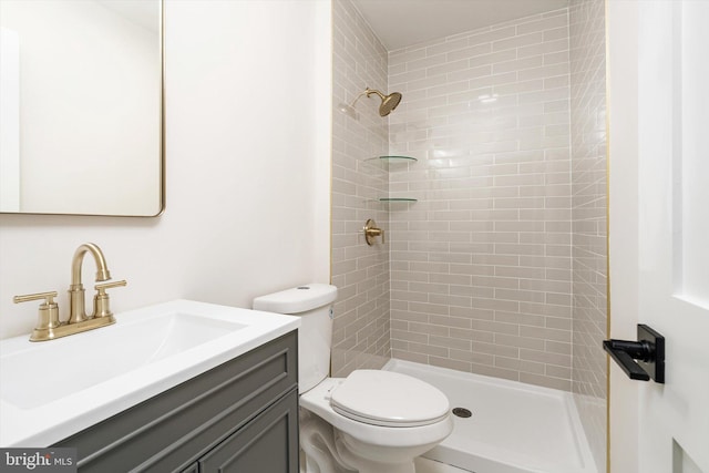 bathroom with vanity, toilet, and tiled shower