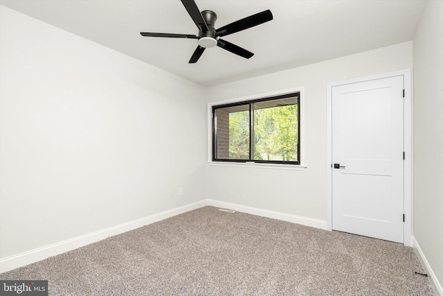 spare room with carpet flooring, a ceiling fan, and baseboards