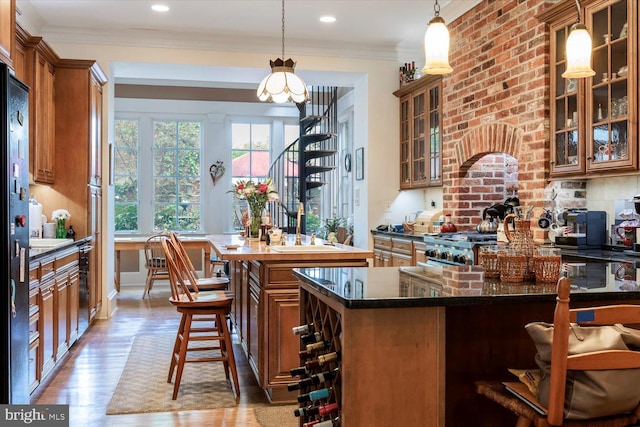 kitchen with a breakfast bar area, a center island, wood finished floors, and brown cabinets
