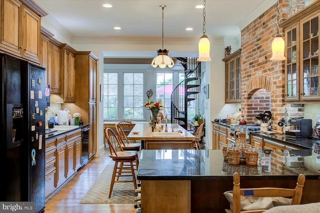 kitchen with crown molding, brown cabinetry, a kitchen breakfast bar, and black fridge