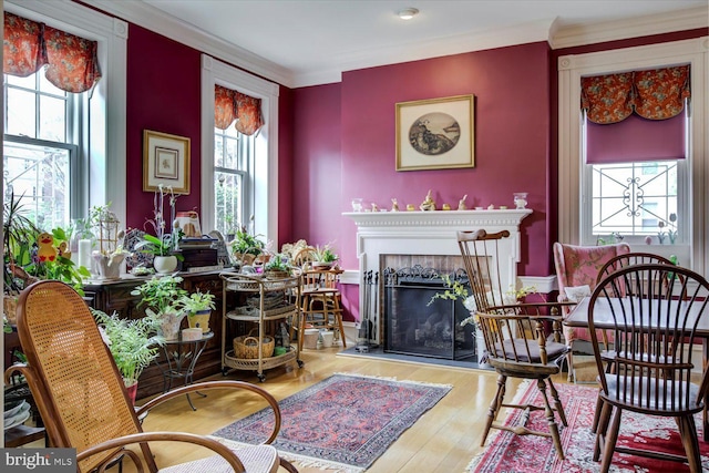 sitting room featuring wood finished floors, a fireplace with raised hearth, and crown molding