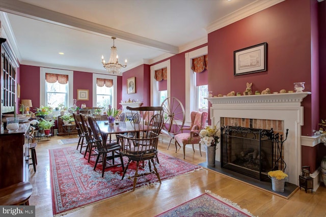 dining area featuring beamed ceiling, a chandelier, a fireplace, crown molding, and wood finished floors