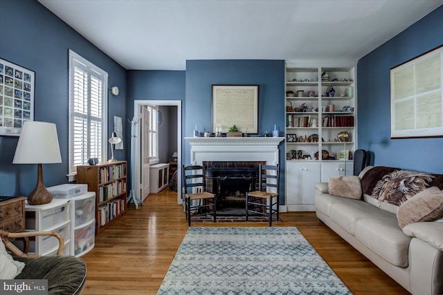 living room featuring a fireplace, wood finished floors, and built in features