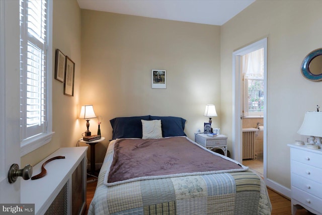 bedroom with baseboards, radiator heating unit, wood finished floors, and ensuite bath