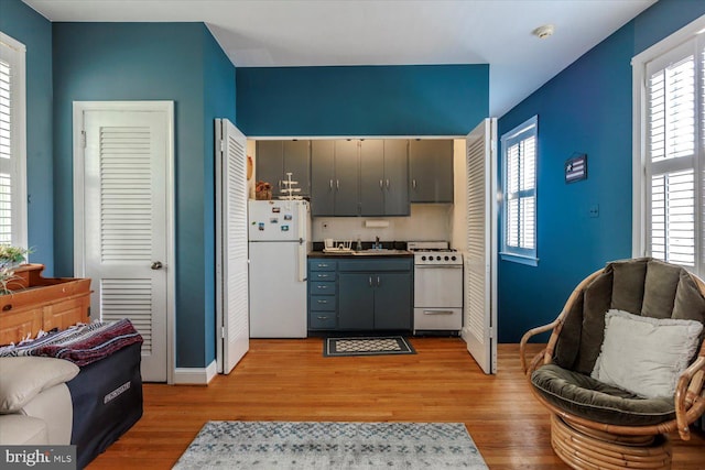 kitchen featuring baseboards, light wood-style flooring, and white appliances