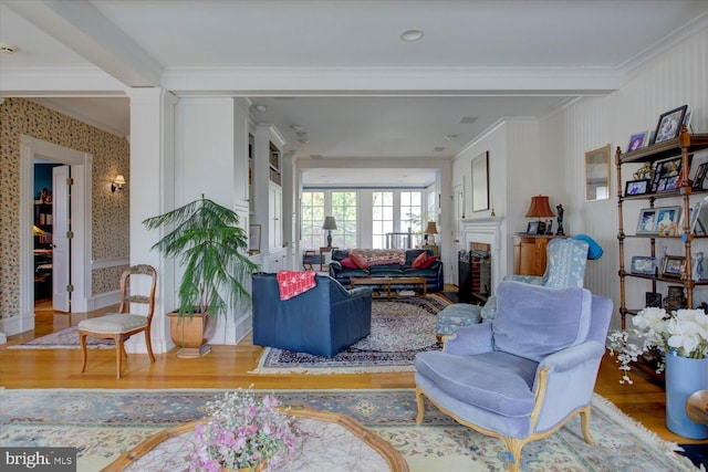 living room with crown molding, wallpapered walls, wood finished floors, and a fireplace