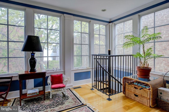 sunroom / solarium featuring crown molding, visible vents, wood finished floors, and baseboards