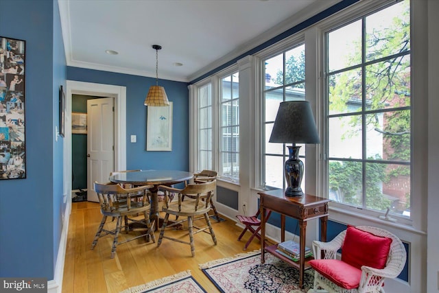 dining space featuring baseboards, light wood-type flooring, a wealth of natural light, and crown molding