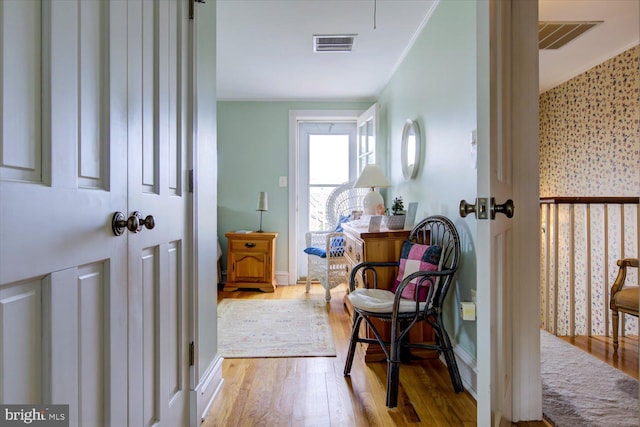 interior space with visible vents, wallpapered walls, wood finished floors, and baseboards