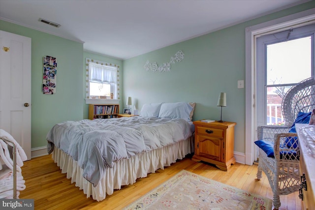 bedroom featuring ornamental molding, visible vents, baseboards, and light wood-type flooring