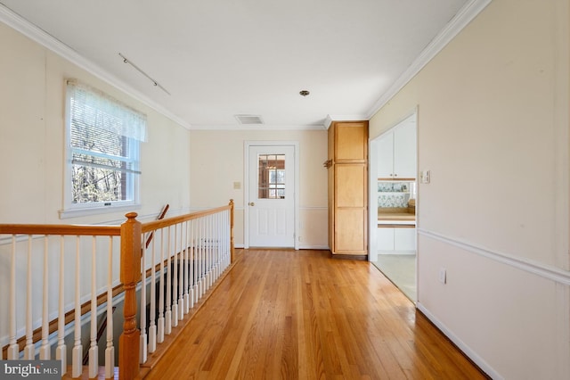 hall with an upstairs landing, ornamental molding, light wood-style floors, and visible vents