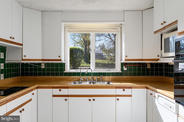 kitchen with dishwasher, white cabinets, decorative backsplash, and a sink