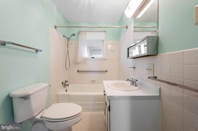 full bathroom featuring toilet, vanity, washtub / shower combination, and tile walls