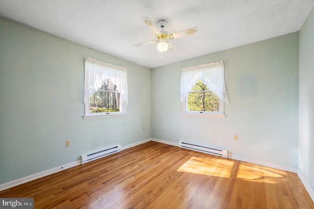 spare room featuring a baseboard heating unit, hardwood / wood-style flooring, and baseboards
