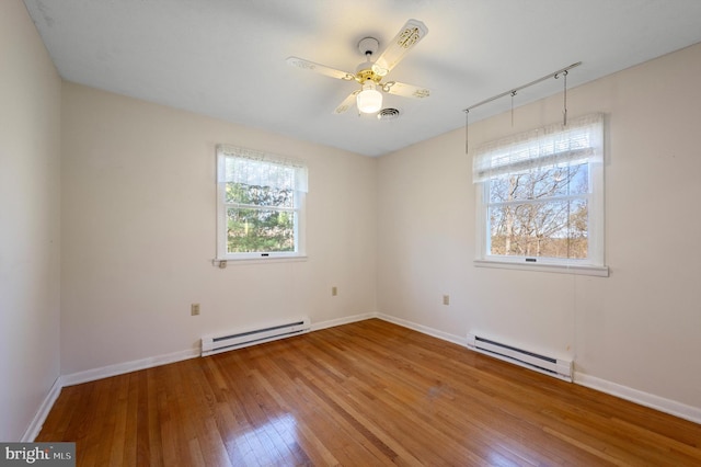 spare room with a baseboard radiator, baseboards, a ceiling fan, and wood-type flooring