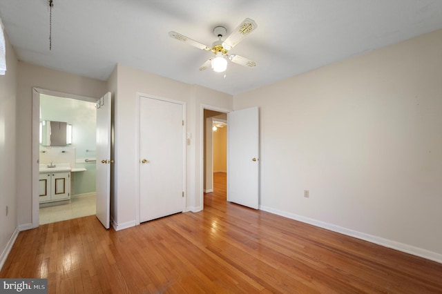 unfurnished bedroom featuring light wood-style flooring, baseboards, and a sink