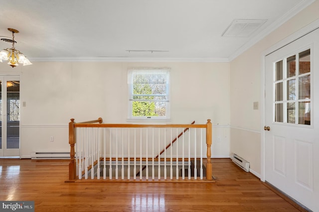 unfurnished room with ornamental molding, wood finished floors, a baseboard radiator, and visible vents