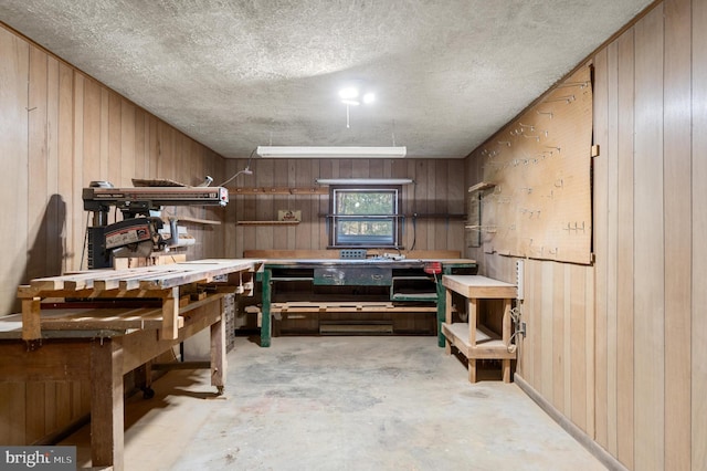 interior space featuring a workshop area, a textured ceiling, and wooden walls