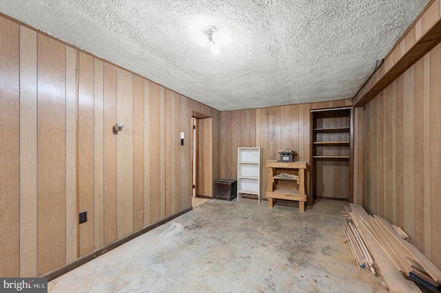 finished basement featuring wooden walls and a textured ceiling