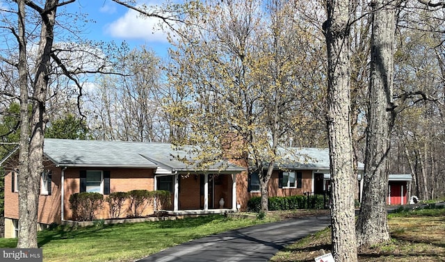 ranch-style house with brick siding, a front yard, roof with shingles, and aphalt driveway