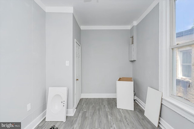 laundry room featuring wood finished floors, baseboards, and crown molding
