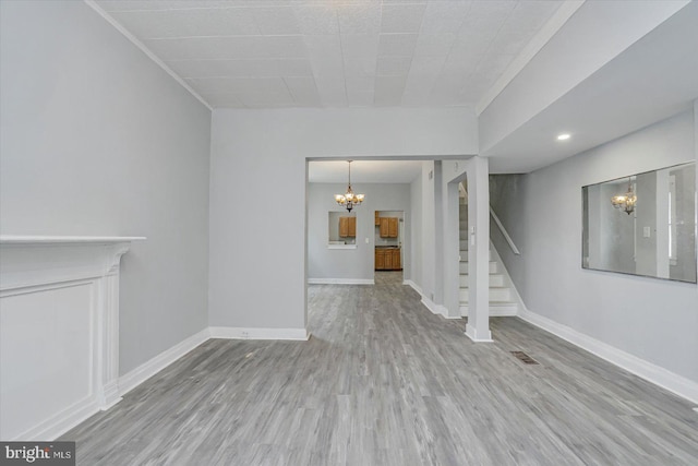 unfurnished living room with a chandelier, stairway, wood finished floors, baseboards, and recessed lighting