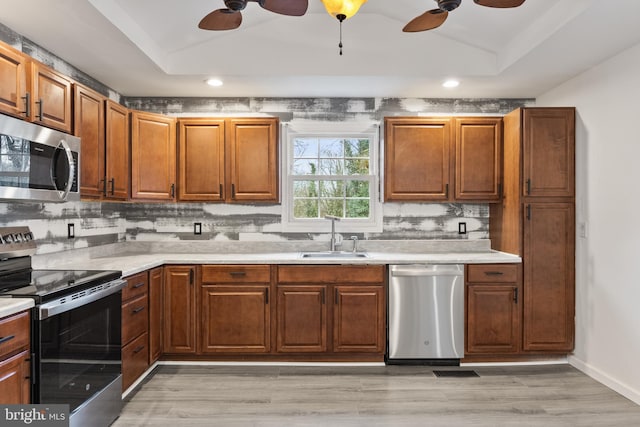 kitchen with a ceiling fan, light countertops, a sink, stainless steel appliances, and backsplash