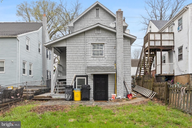 back of house featuring stairs, a fenced backyard, and a chimney