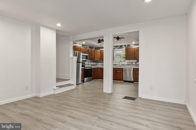 kitchen featuring light wood-type flooring, light countertops, decorative backsplash, stainless steel appliances, and ceiling fan