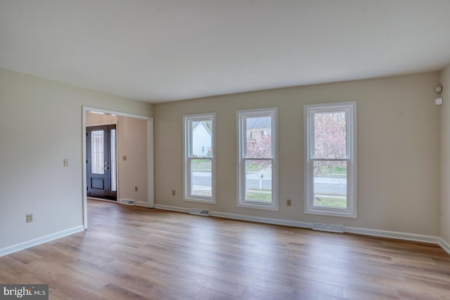 unfurnished room featuring baseboards, visible vents, and wood finished floors