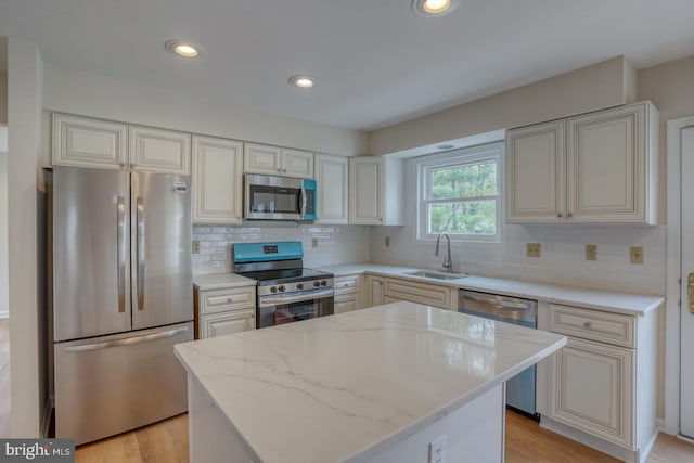 kitchen featuring a sink, appliances with stainless steel finishes, tasteful backsplash, and light stone countertops