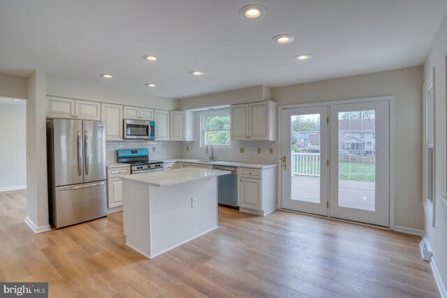 kitchen with recessed lighting, light countertops, a sink, appliances with stainless steel finishes, and backsplash