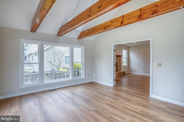 empty room with baseboards, vaulted ceiling with beams, and light wood-style flooring