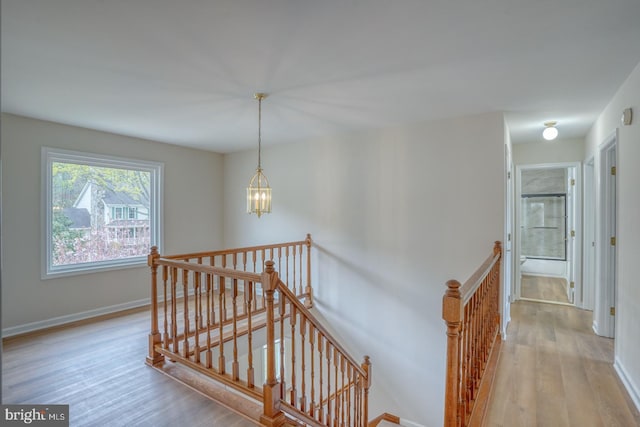 stairway with baseboards, wood finished floors, and a chandelier
