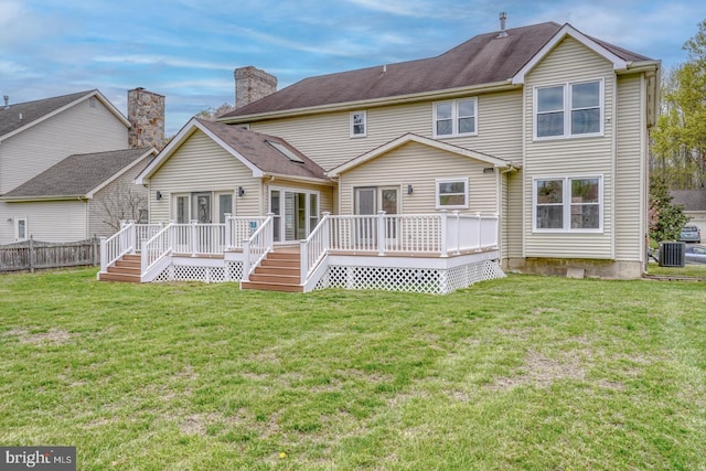 rear view of property featuring a lawn, fence, a wooden deck, and central air condition unit