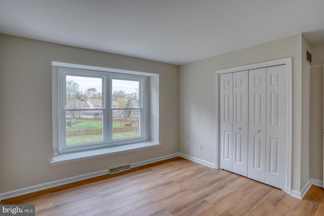 unfurnished bedroom with baseboards, visible vents, light wood finished floors, and a closet