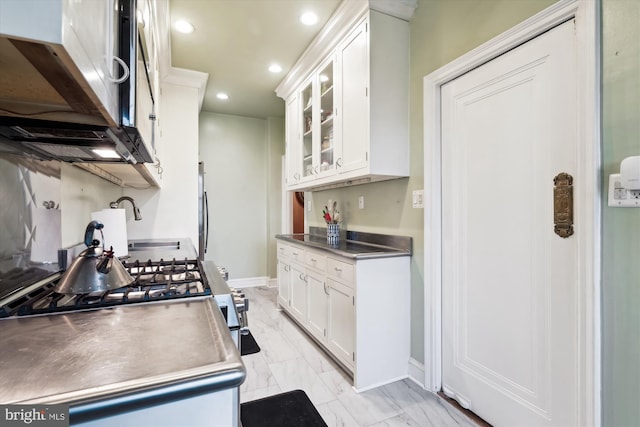 kitchen featuring glass insert cabinets, stainless steel counters, white cabinets, recessed lighting, and marble finish floor
