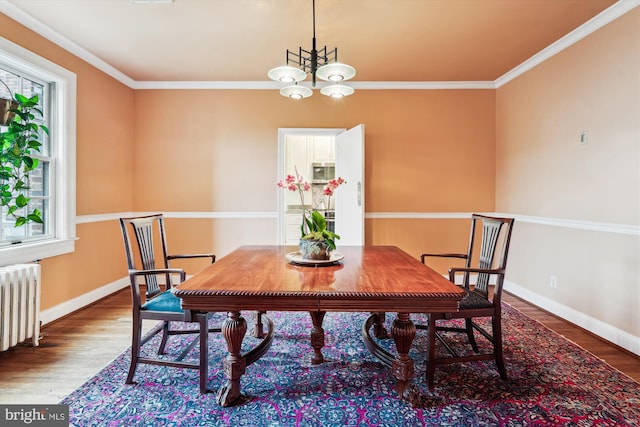 dining space with ornamental molding, radiator heating unit, wood finished floors, and baseboards