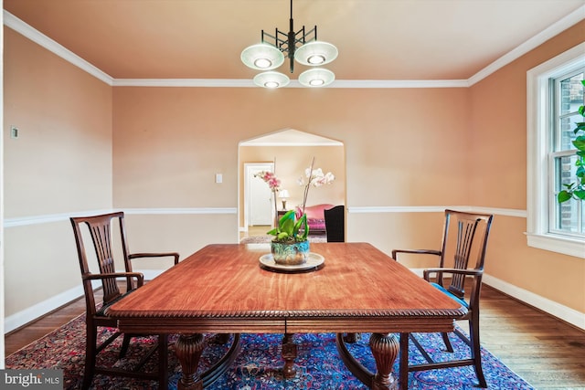 dining space with a chandelier, crown molding, wood finished floors, and baseboards