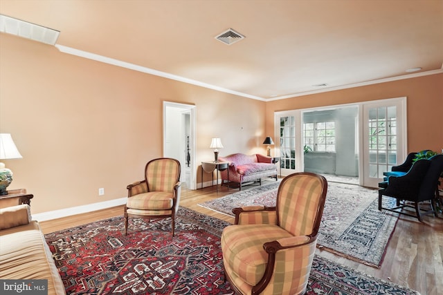 living area with visible vents, baseboards, ornamental molding, and wood finished floors