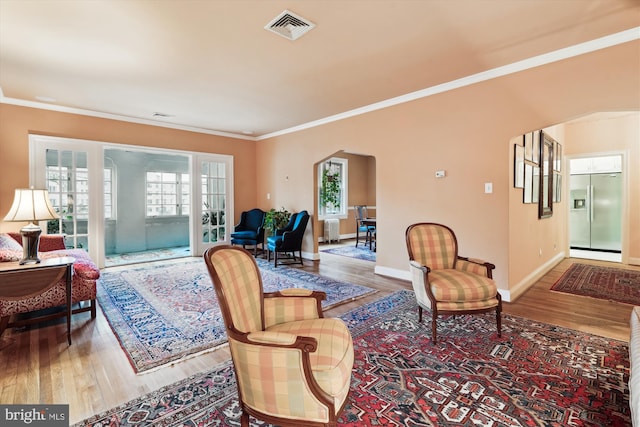 living room with arched walkways, wood finished floors, and visible vents