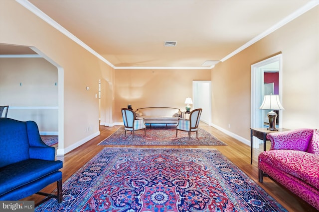 living area featuring visible vents, baseboards, arched walkways, ornamental molding, and wood finished floors