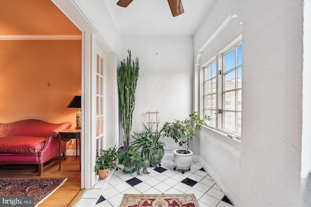 living area with baseboards, a ceiling fan, and wood finished floors