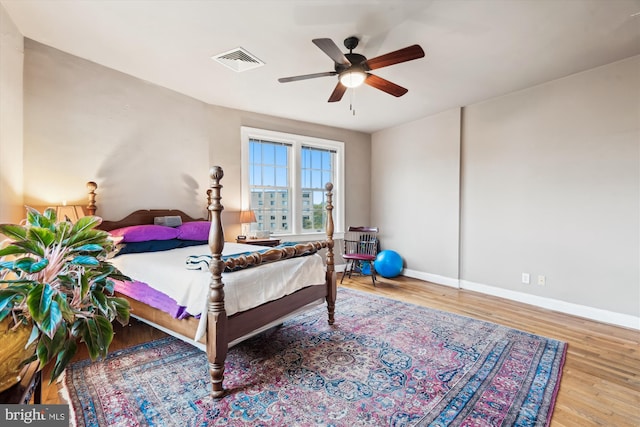 bedroom with wood finished floors, ceiling fan, baseboards, and visible vents