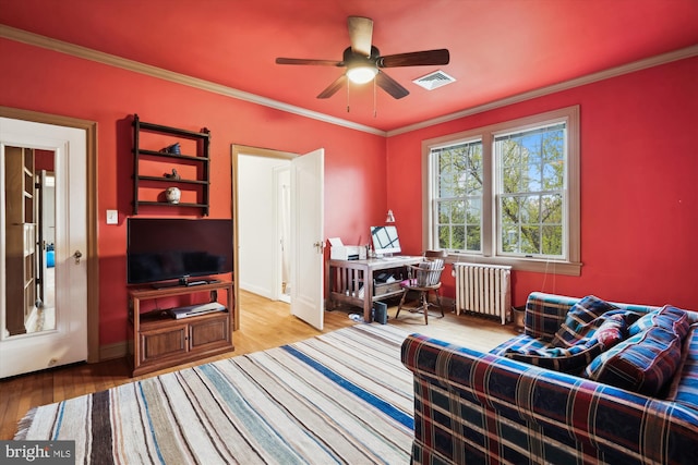 interior space with wood finished floors, radiator heating unit, a ceiling fan, and visible vents